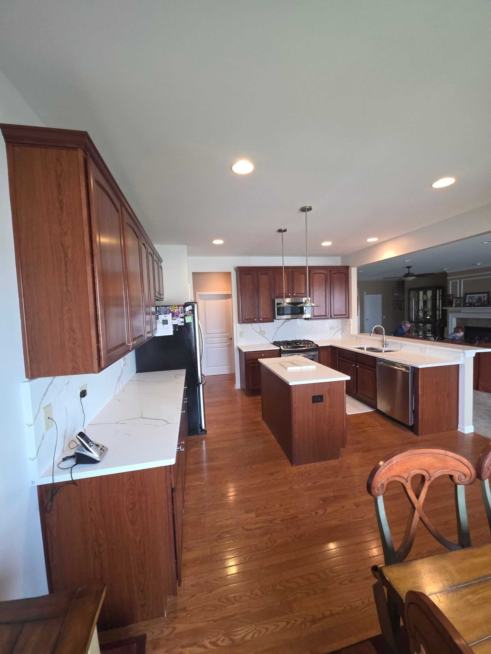 Finished kitchen with a bold-veined white quartz island and peninsula, cherry cabinets and repainted gray walls