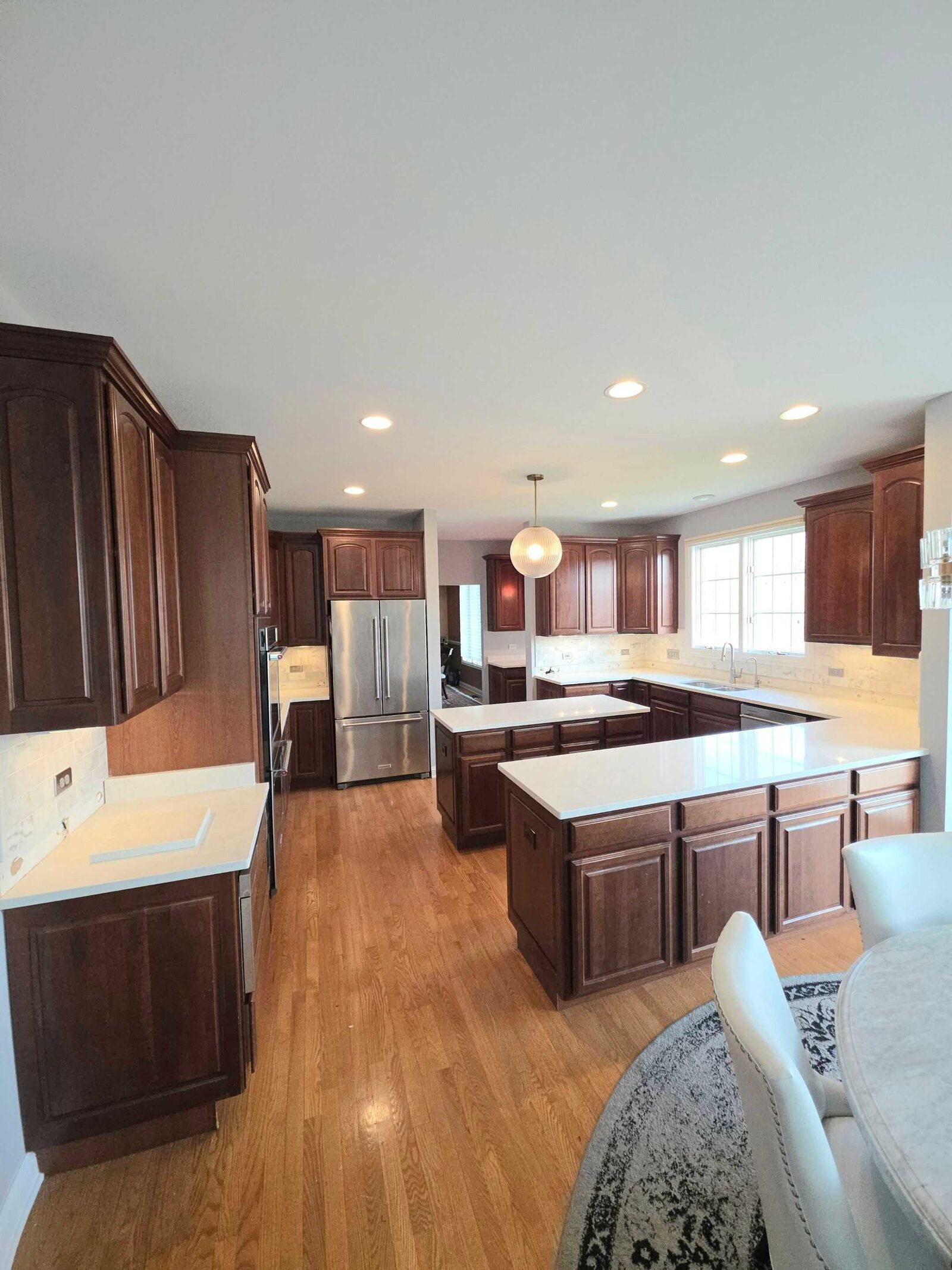 The finished kitchen in white quartz, island and perimeter, with cherry cabinets and oak floors
