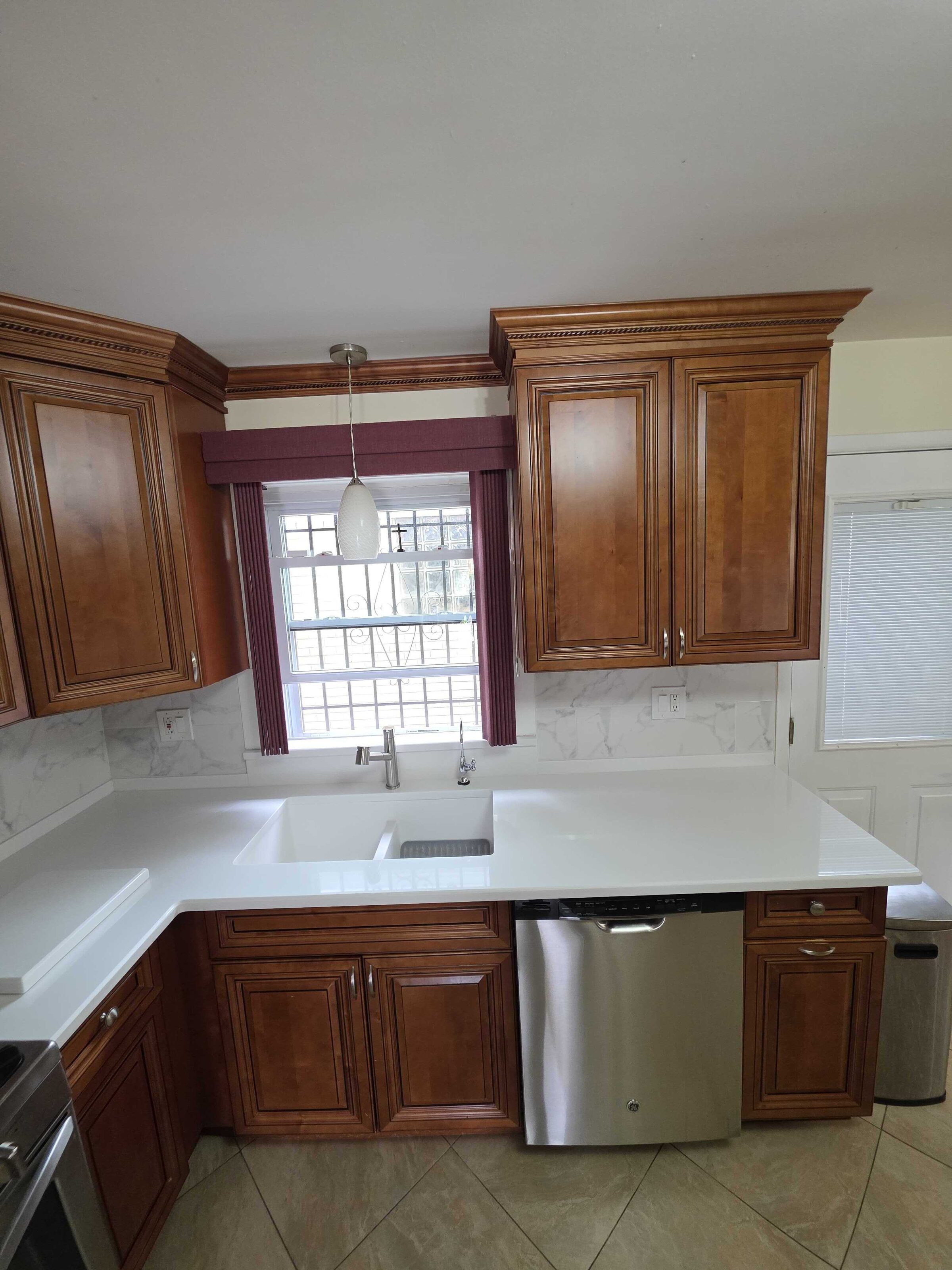 New quartz at the sink under a glass-block window, dishwasher to the right