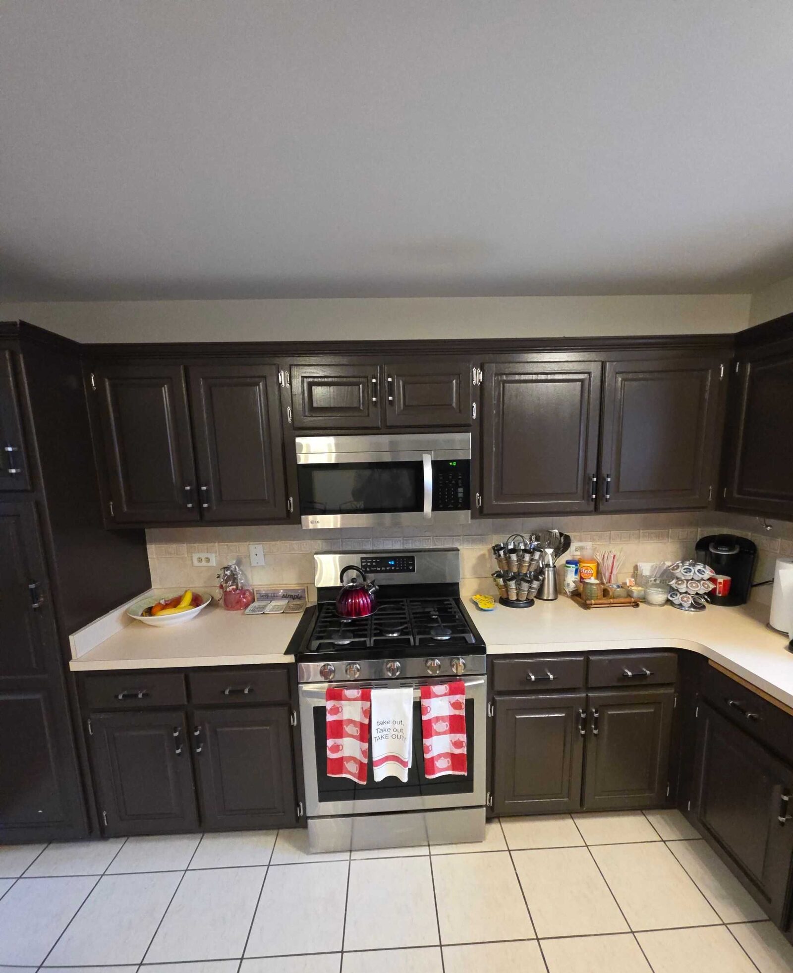 The same kitchen before, in beige laminate with the range wall crowded with jars and canisters