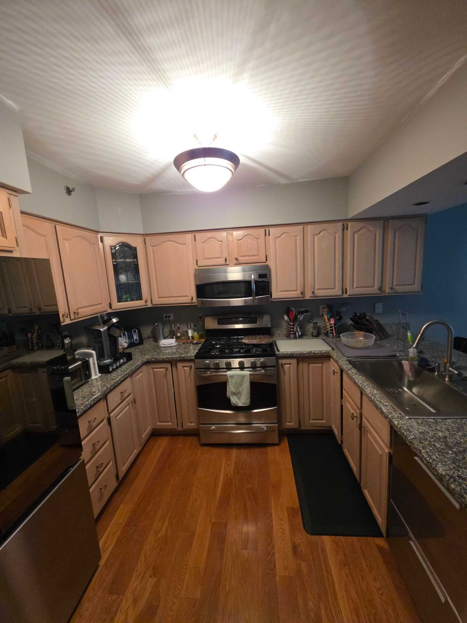 Before: the old granite counters at the sink, pickled oak cabinets and a dark tile floor