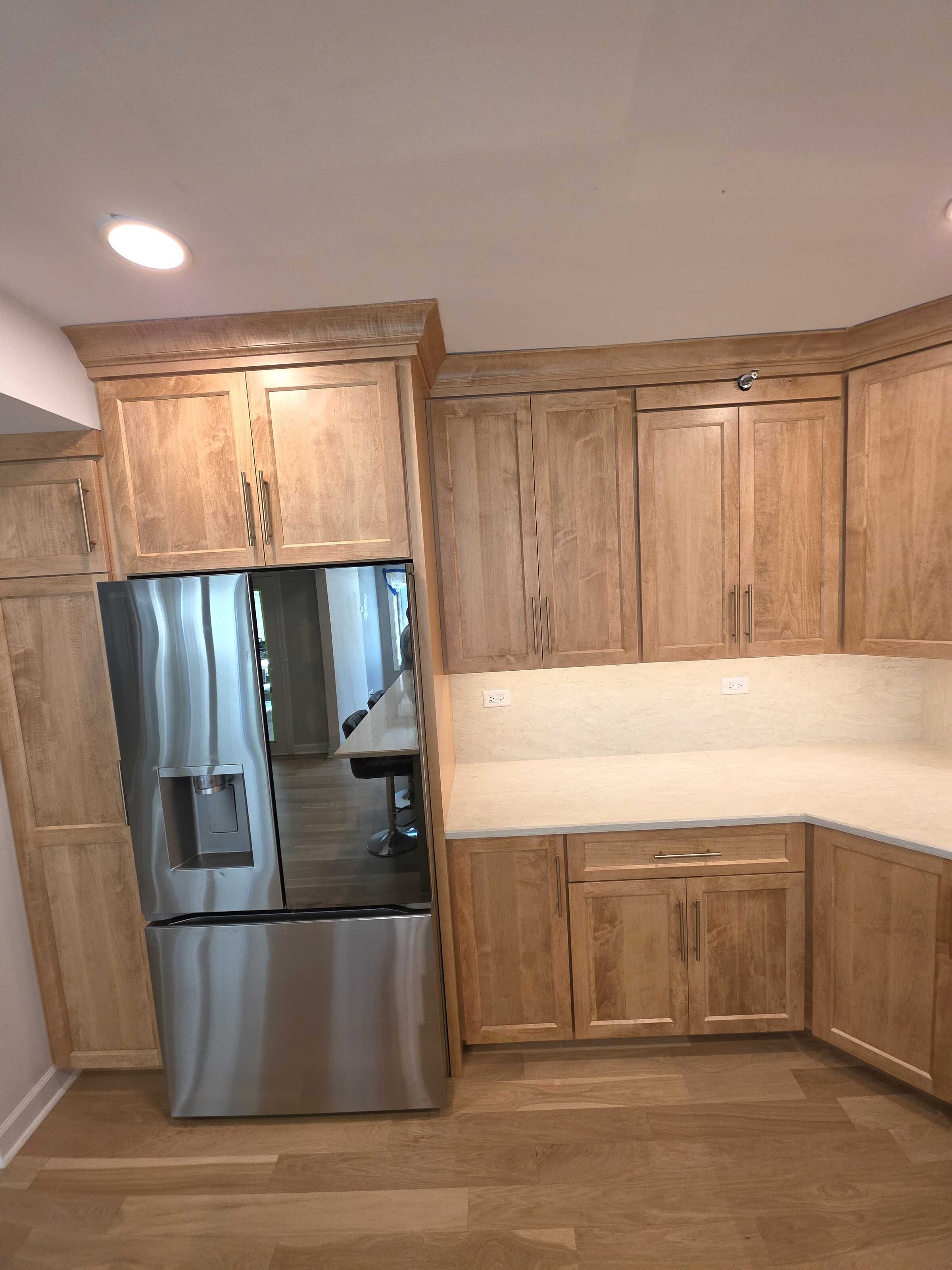 New maple cabinets and cream quartz turning the corner beside the refrigerator