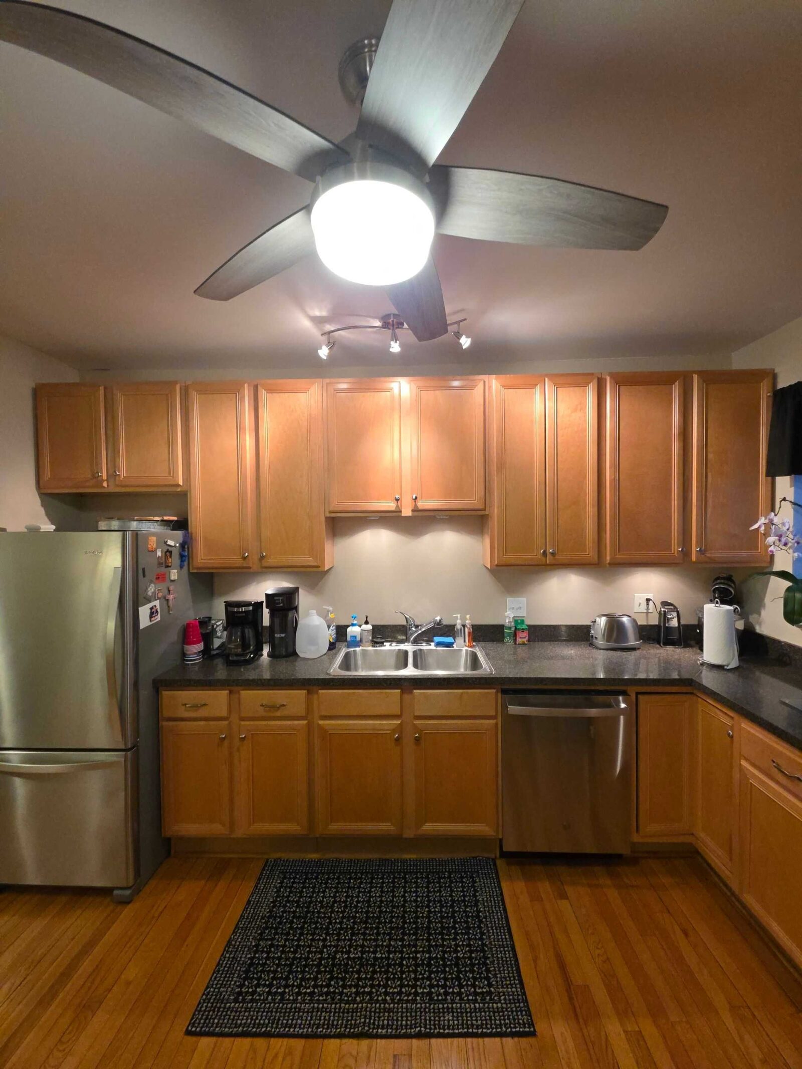 Before: the U of the kitchen in dark counters, maple cabinets and a black floor mat