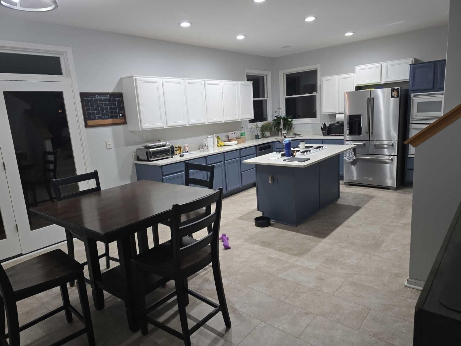 Open-plan view with the dining table in front of the navy and white kitchen