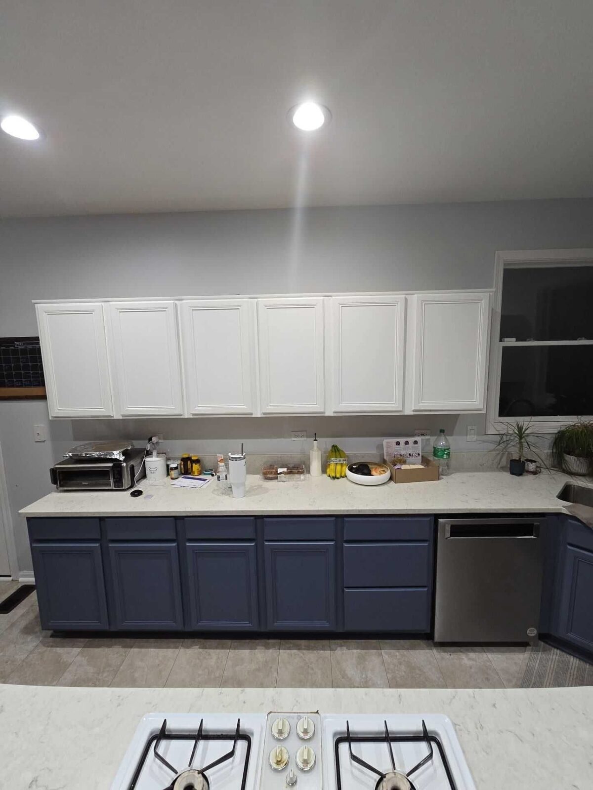 The perimeter run in white quartz, navy base cabinets and a subway tile backsplash