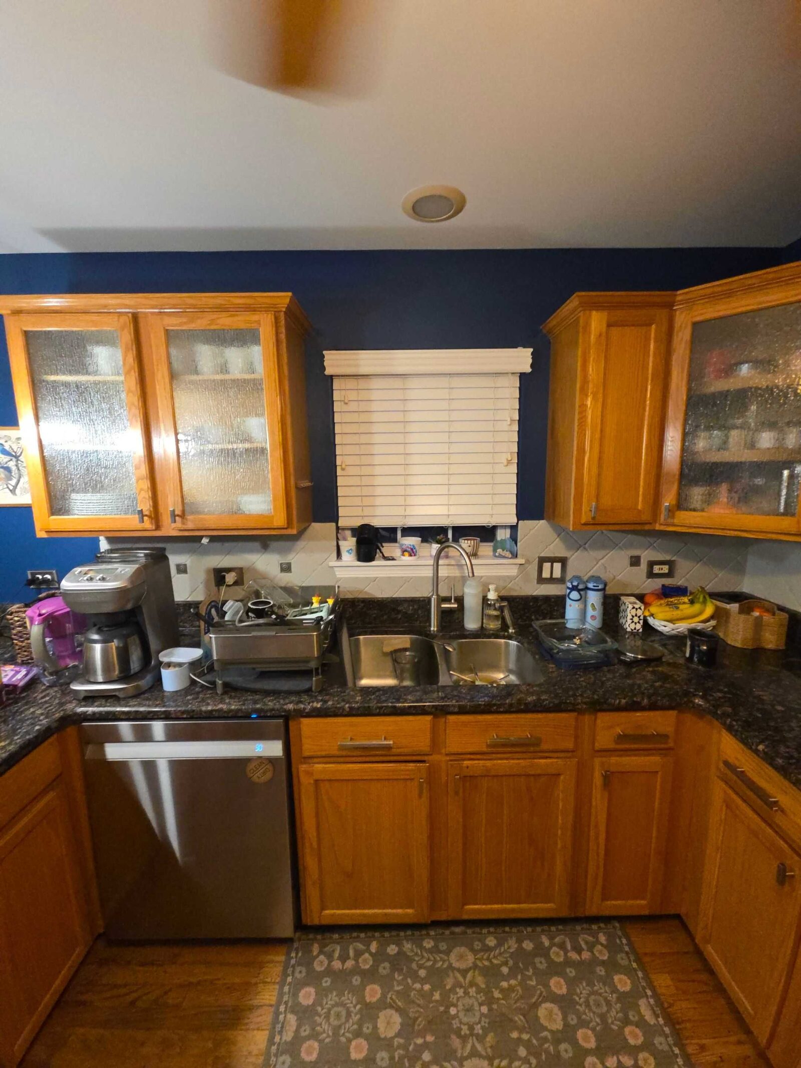 The old dark granite along the sink and dishwasher run, oak cabinets above