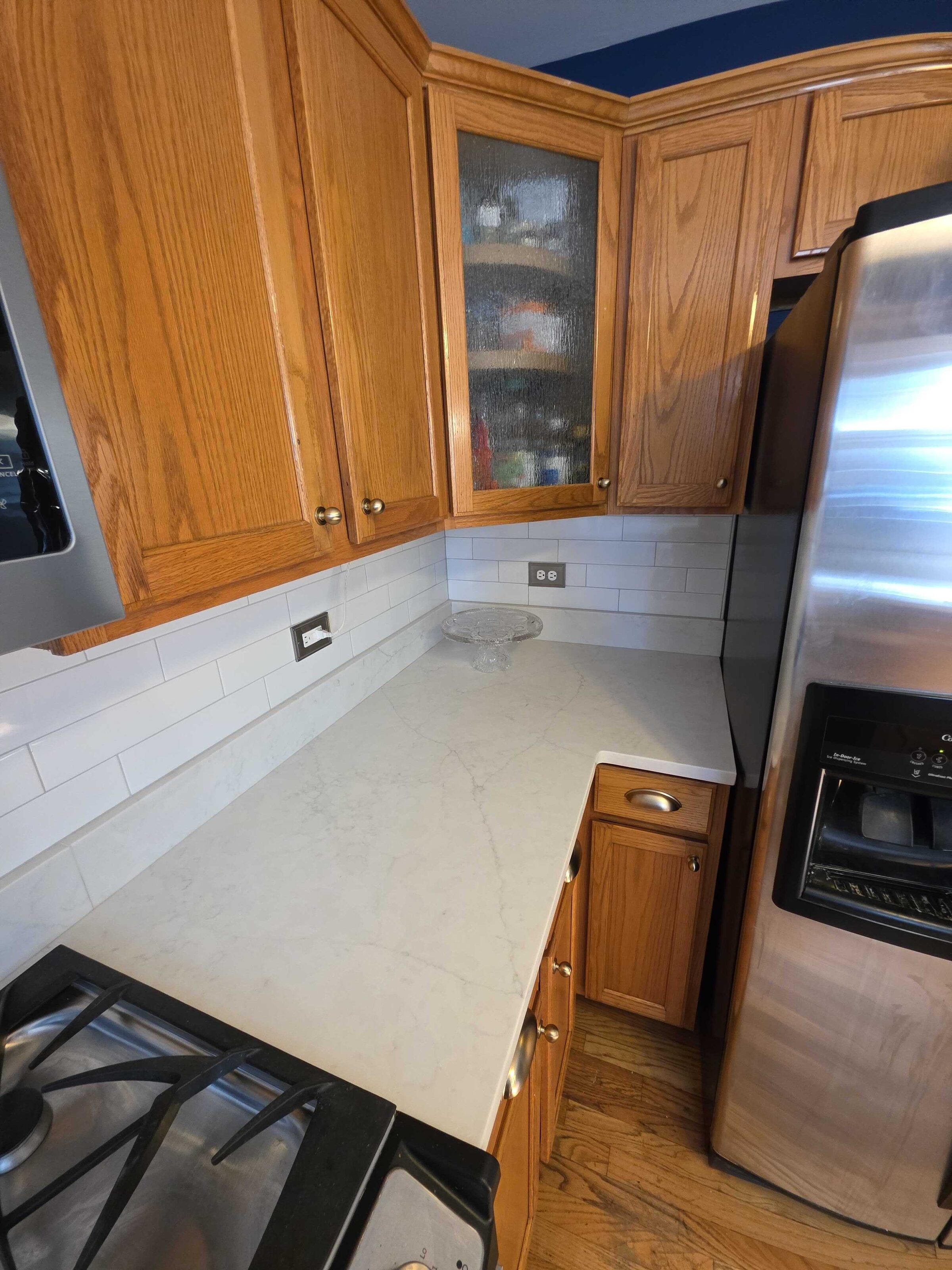 Quartz corner beside the refrigerator, showing the counter depth against the oak