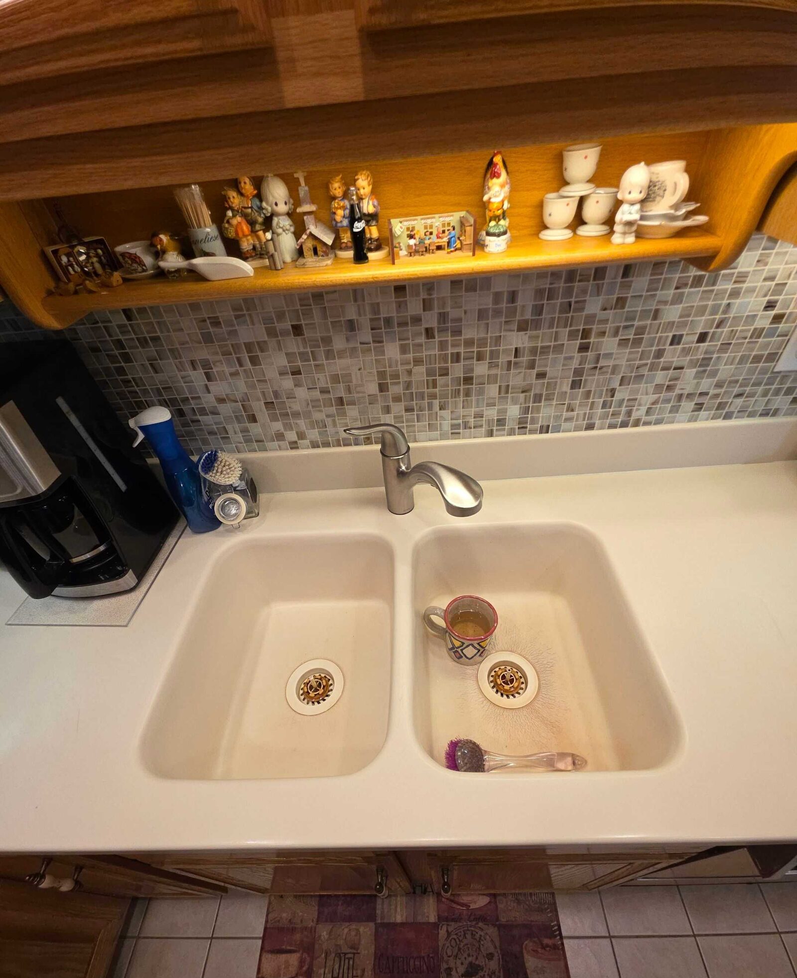 The original almond laminate top with its molded-in double sink and a coffee cup in the basin