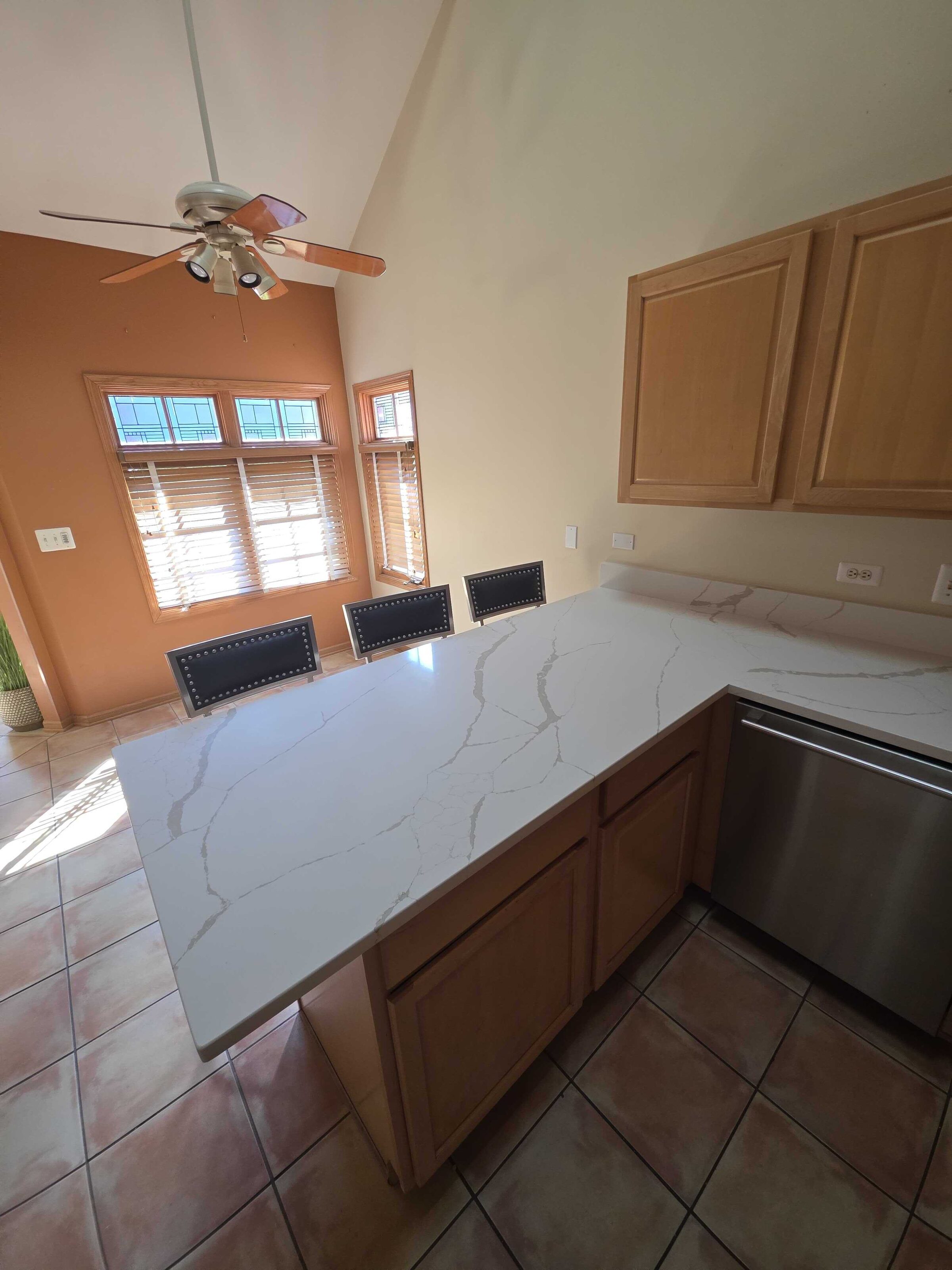 The quartz counter running to the corner window, seen from the dining end