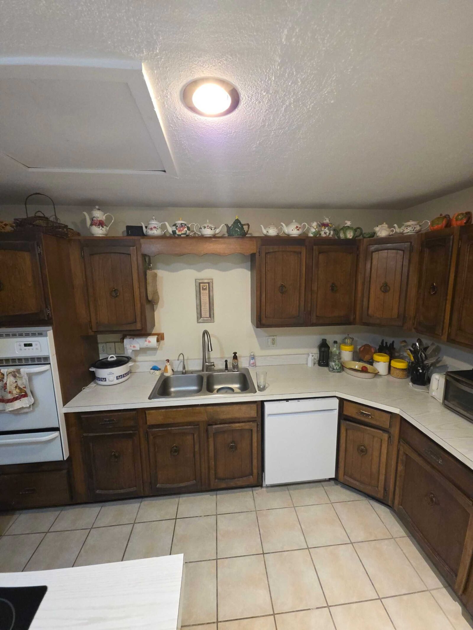 The same sink run before the work, in worn cream laminate with canisters crowding the corner