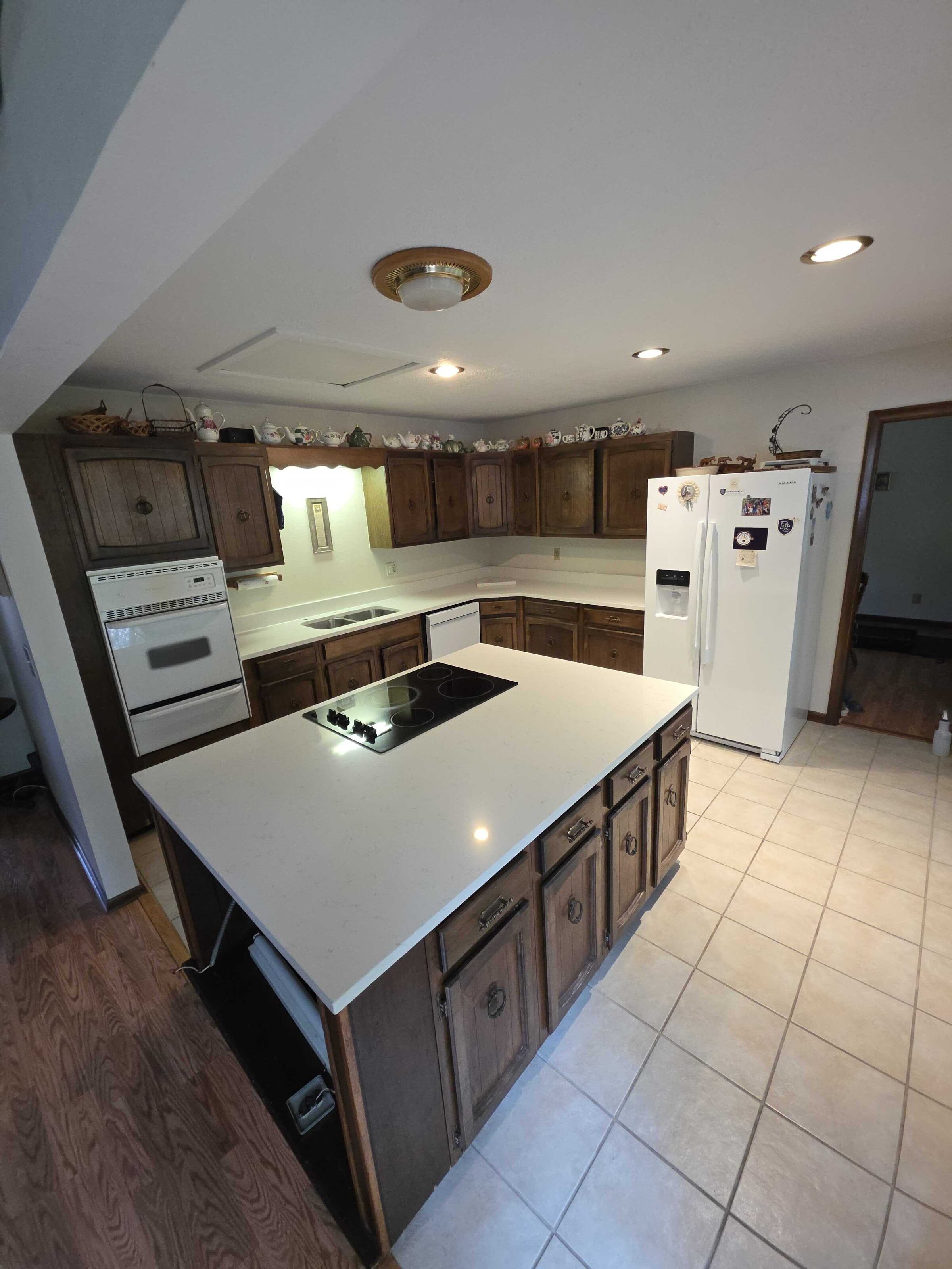 The cooktop island in new white quartz, seen from the far side of the kitchen