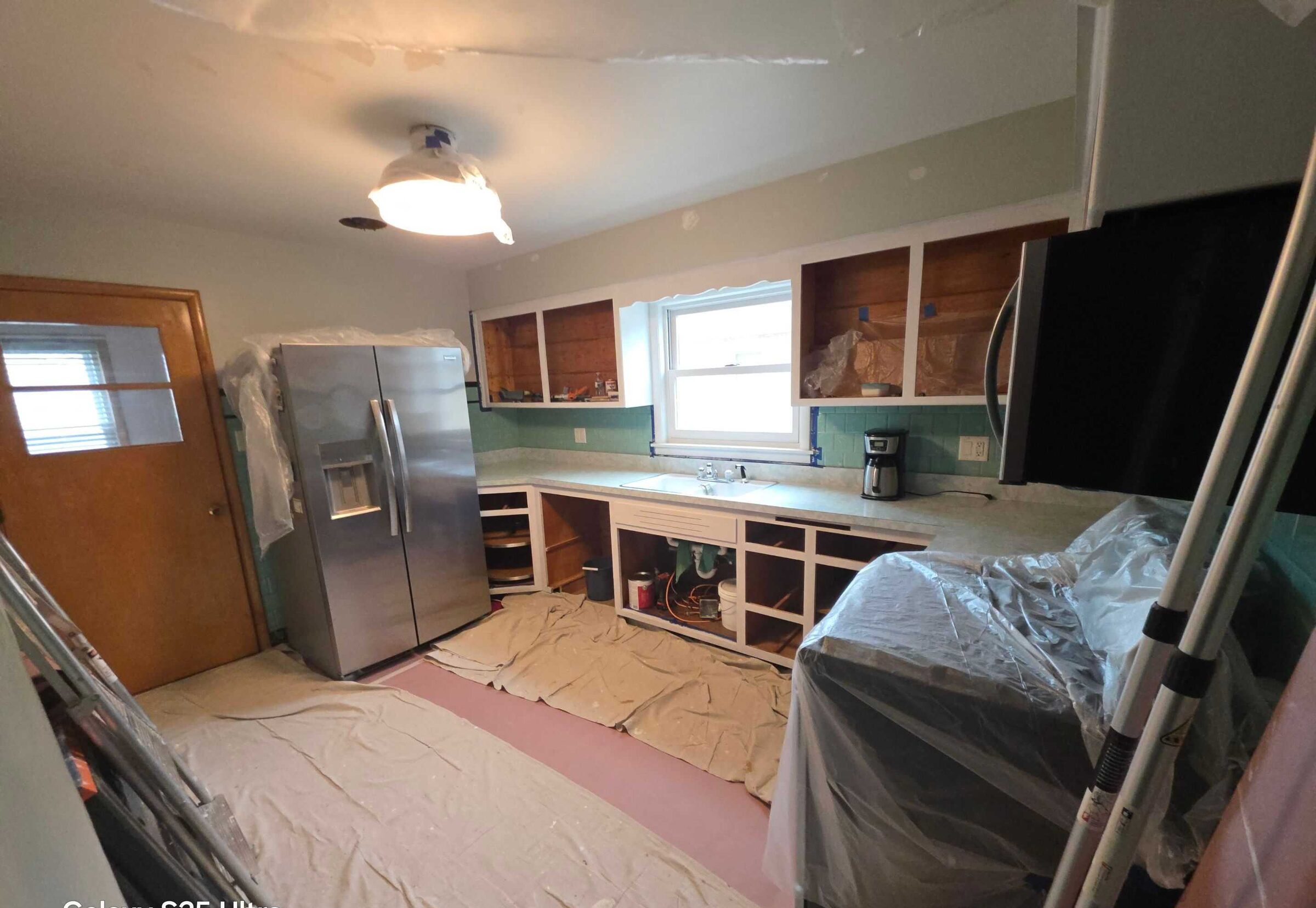 Mid-job: the refrigerator pulled clear and the counters stripped ready for templating