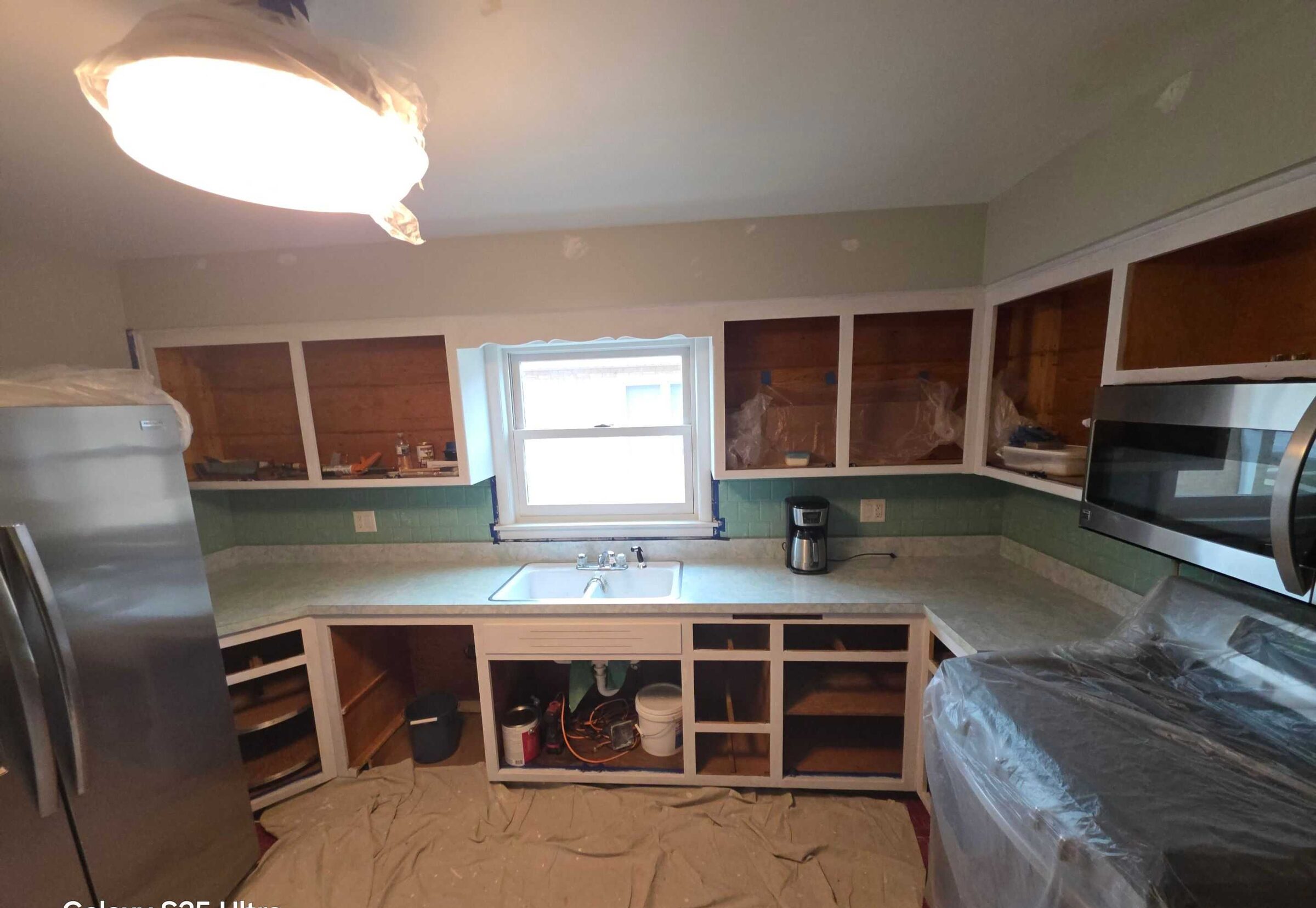 The same galley stripped back, cabinet boxes open and everything sheeted for the work