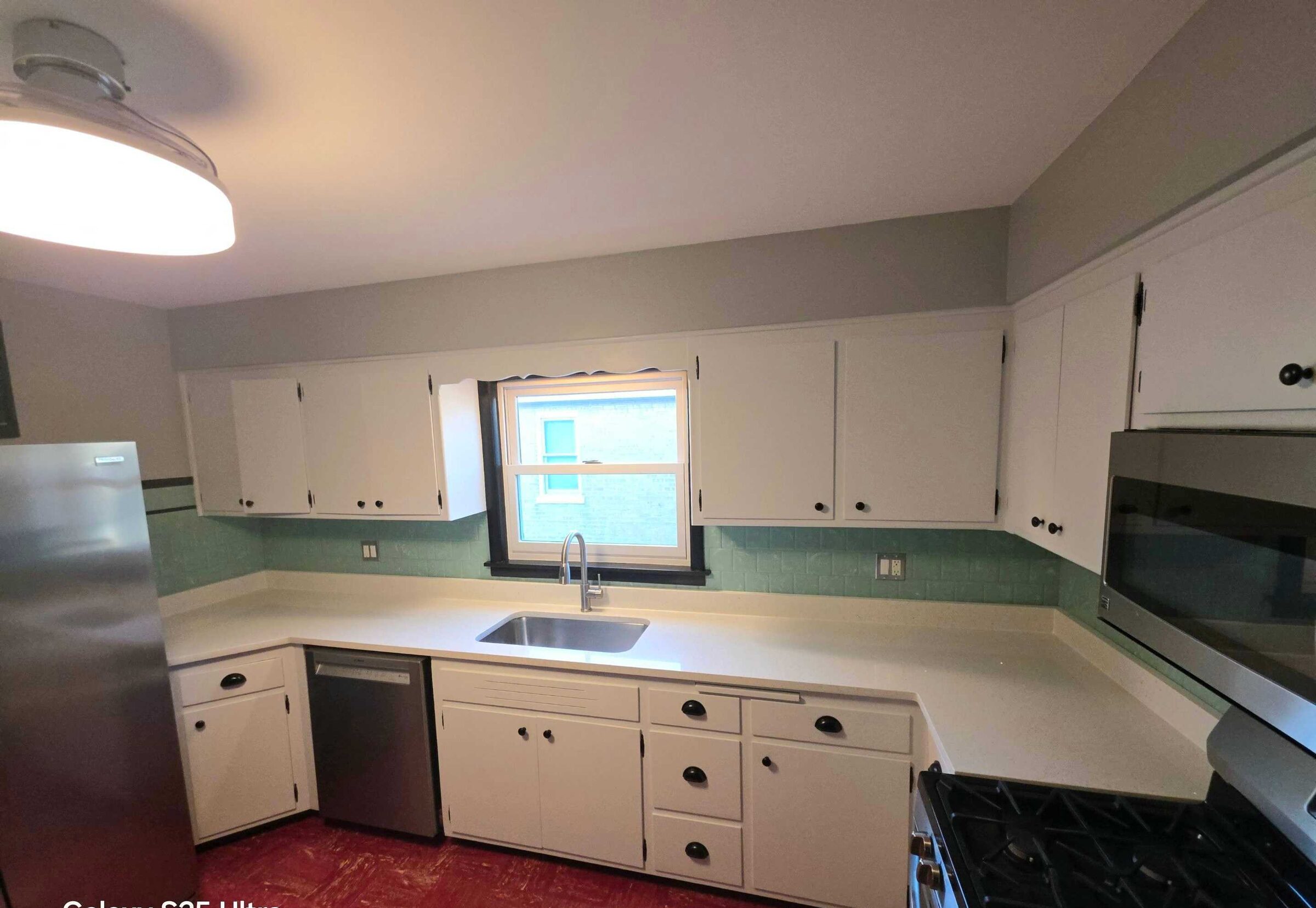 The finished galley with white counters both sides, refinished cabinets and the original mint wall tile