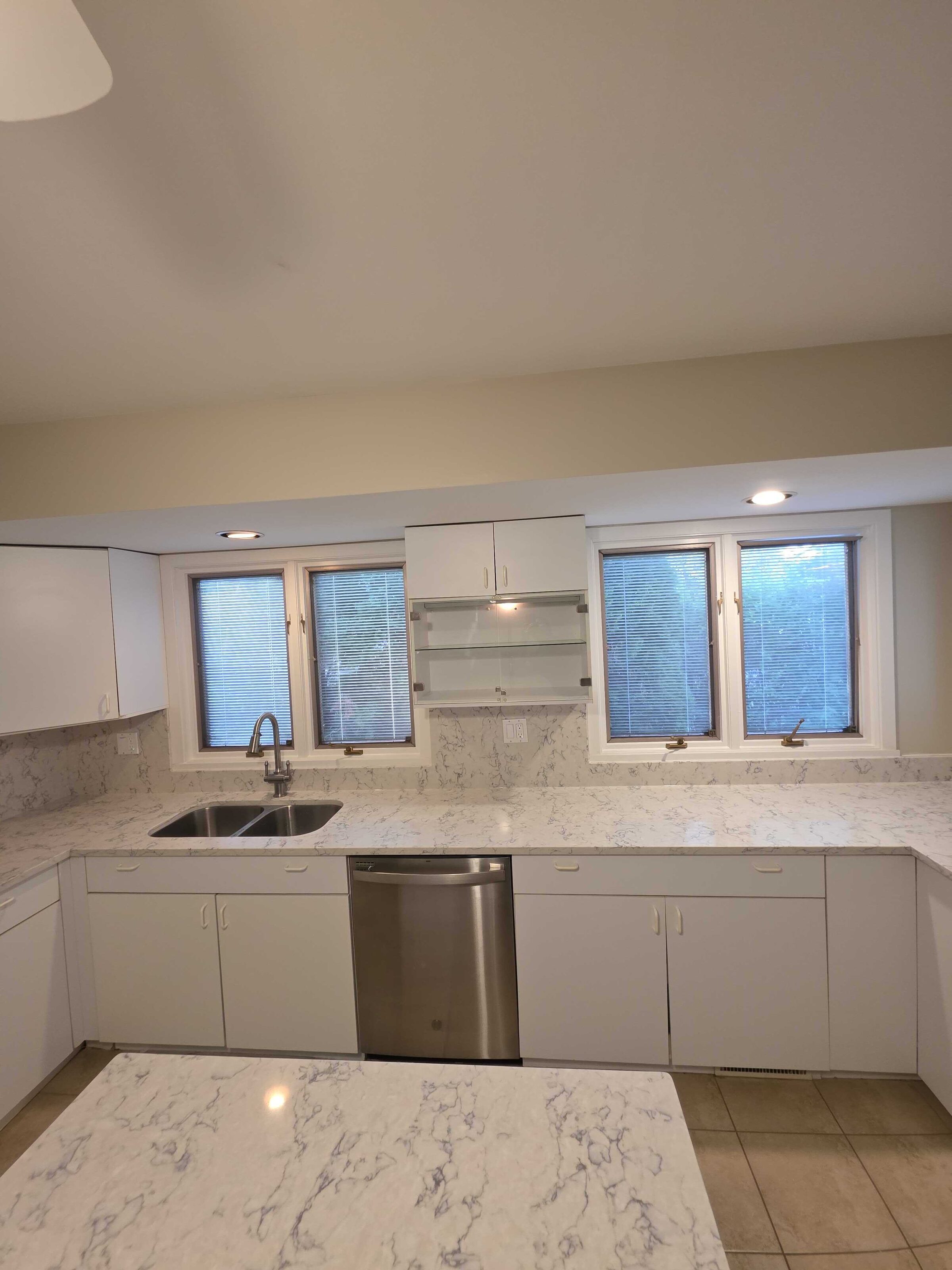 The finished run along the window wall, quartz carrying past the dishwasher