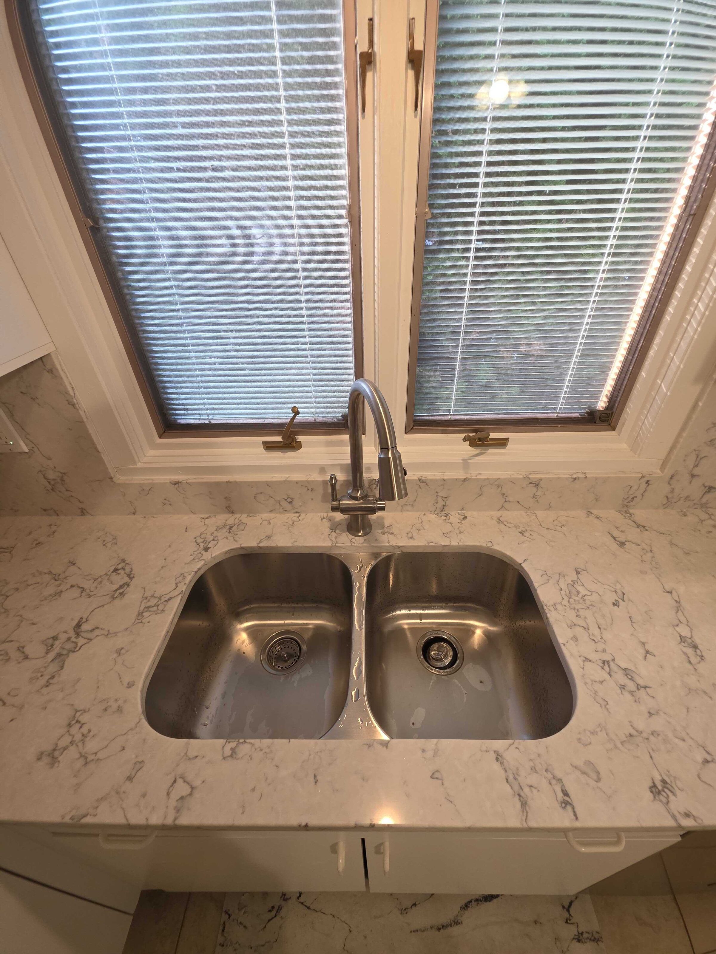 Stainless double sink set into the new quartz under a corner window