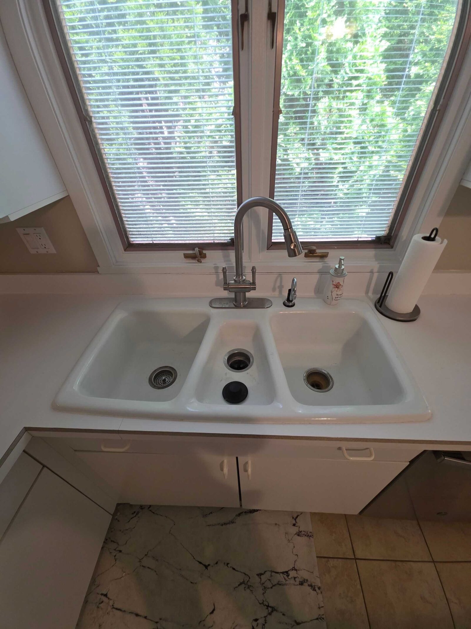 The original molded triple-bowl sink and white counter at the same window