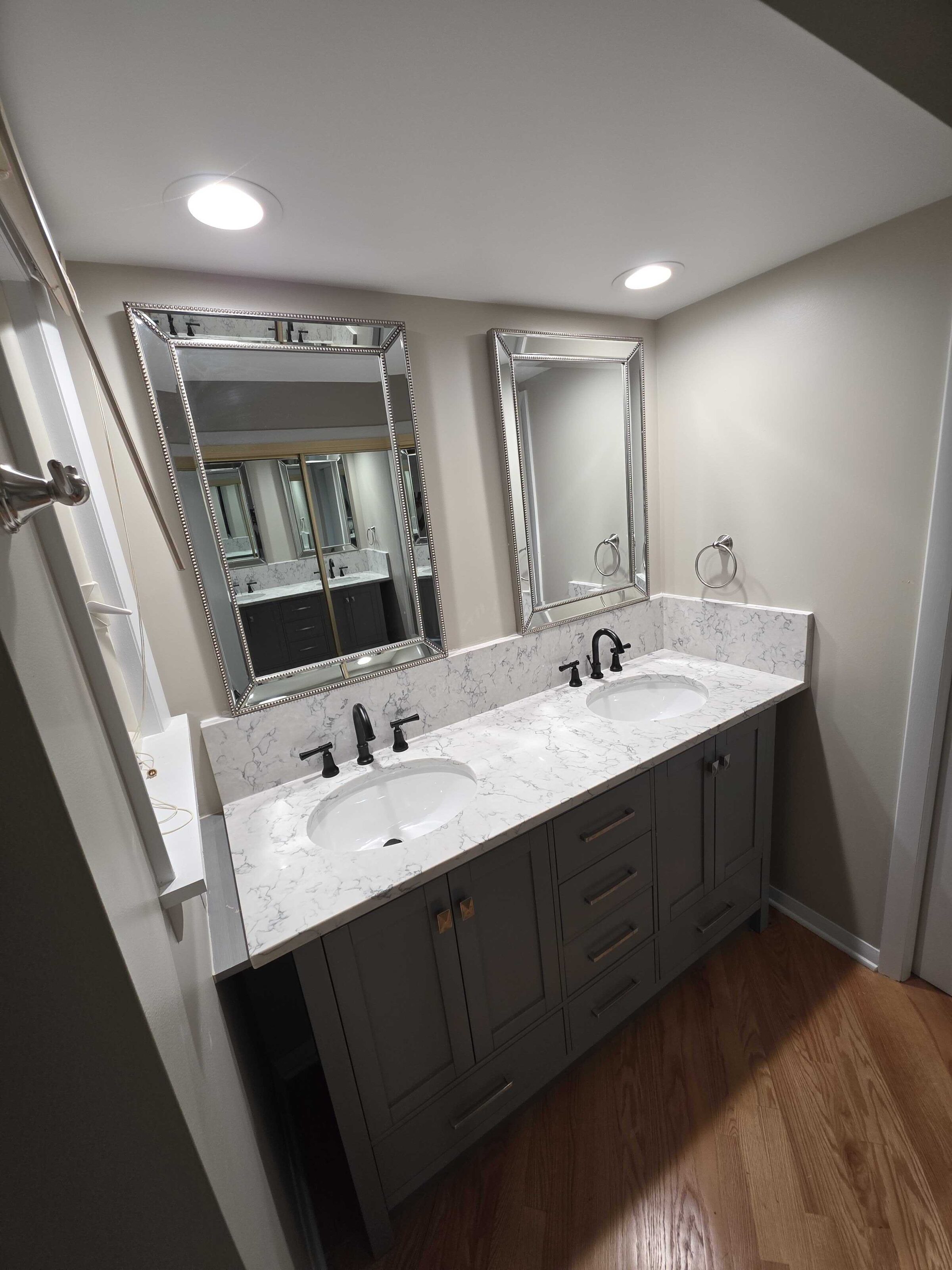 Gray double vanity in the same marble-look quartz, twin mirrors above