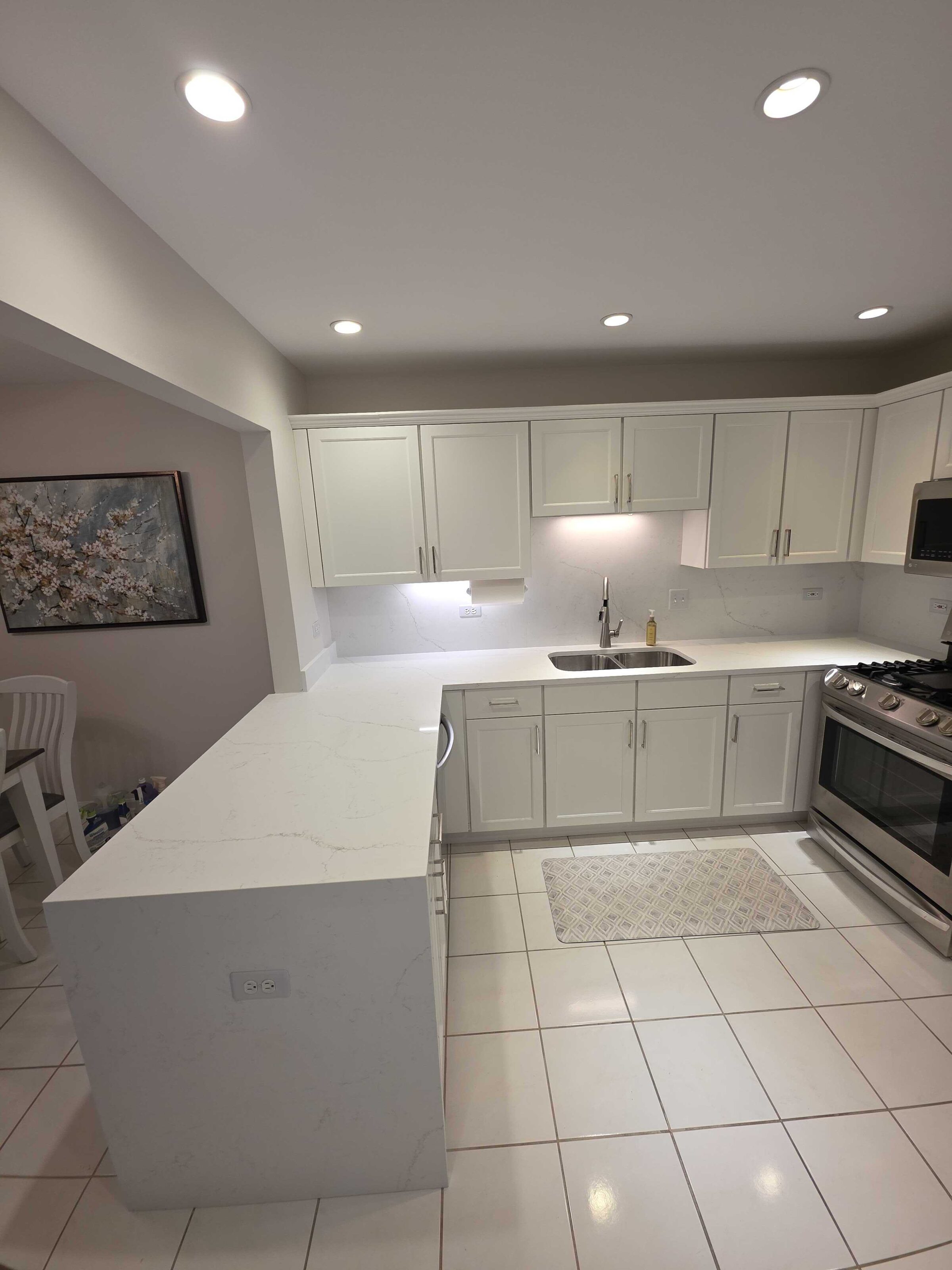 The finished peninsula end, quartz edge above white cabinets and tile