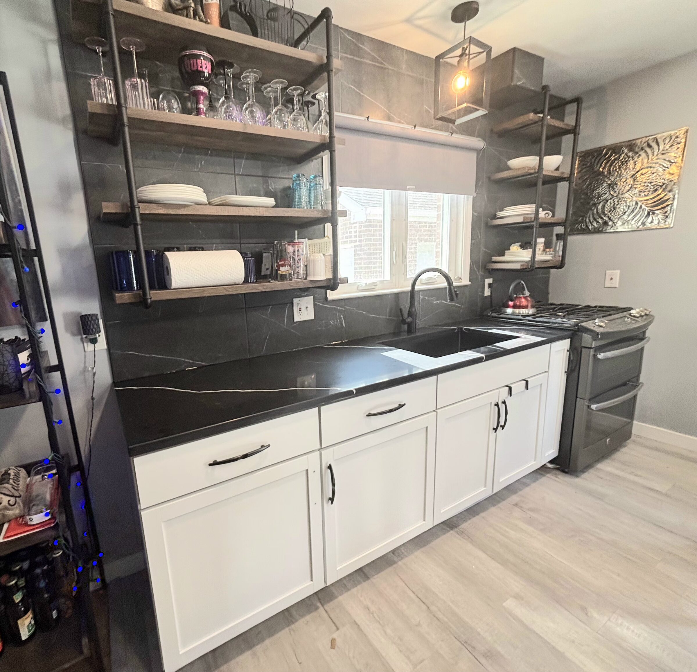 Black quartz with a single white vein running the length of a white shaker kitchen, under industrial open shelving