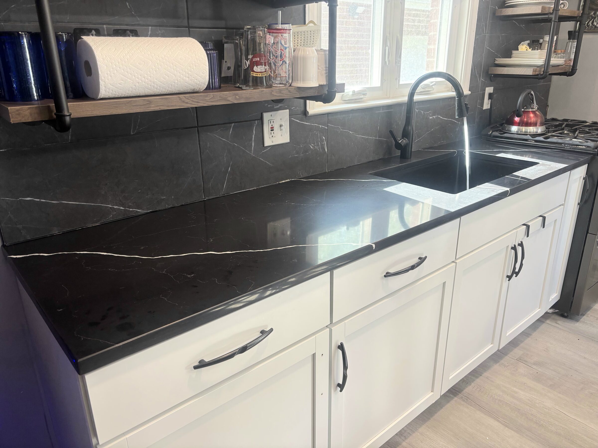 The new black quartz at the sink, water running from a matte black faucet