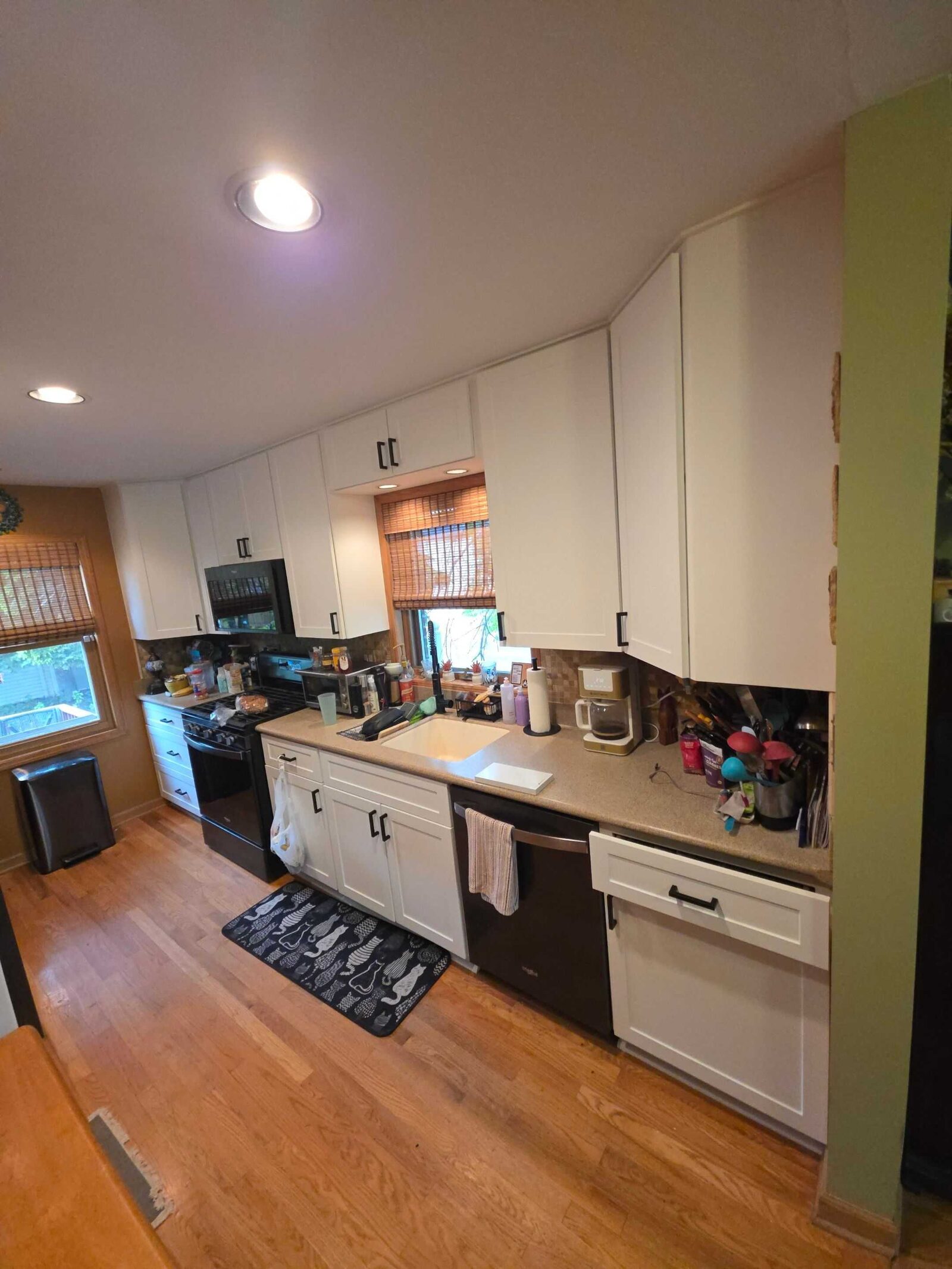 The same galley before, its tan counter running past a black range under white cabinets