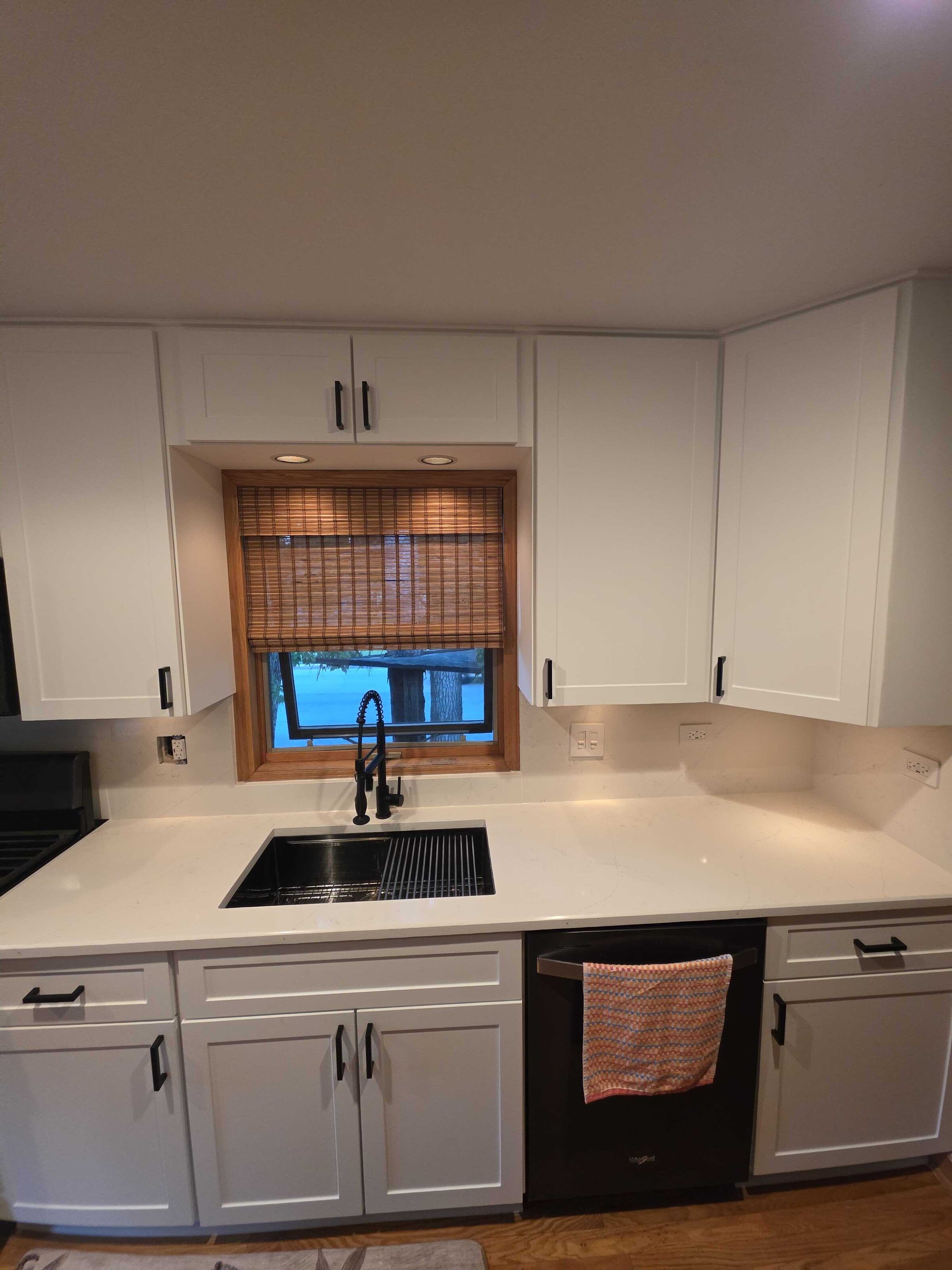 The new counter at the dishwasher, a towel over the door and the black tap beyond